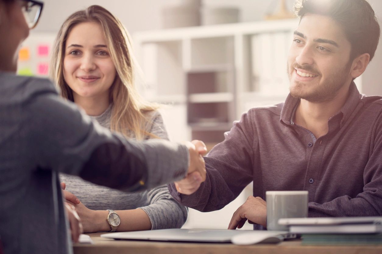 A realtor sealing a deal with a man and woman